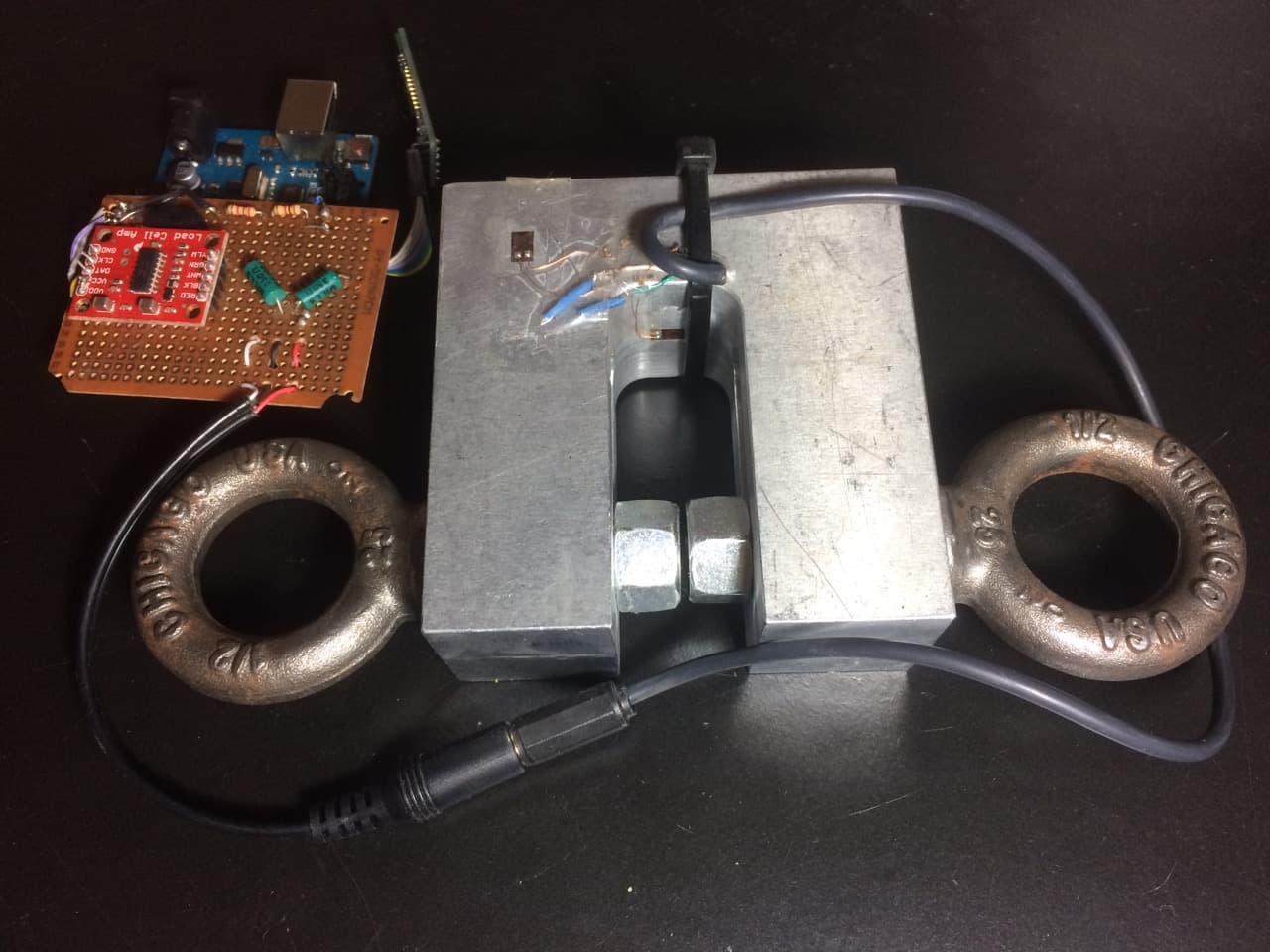 A U-shaped block of steel the size of paperback book with two eyebolts on opposite sides. A wire lead coming off of it to a circuit board.